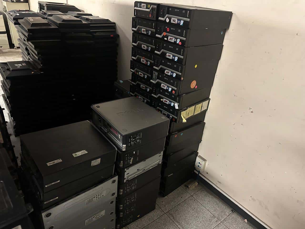 Computadoras de escritorio apiladas en una oficina, listas para la recolección empresarial